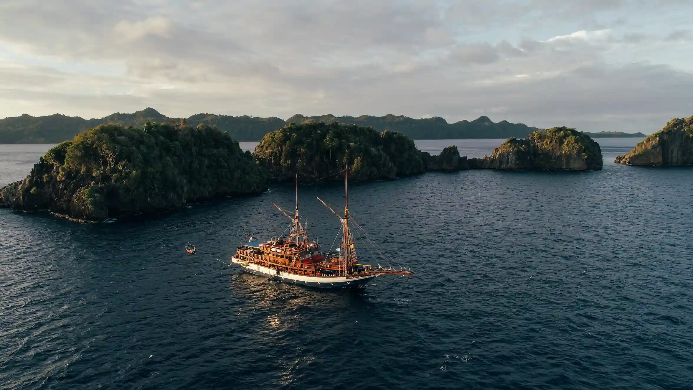 Phinisi liveaboard schooner anchored among Raja Ampat limestone karsts